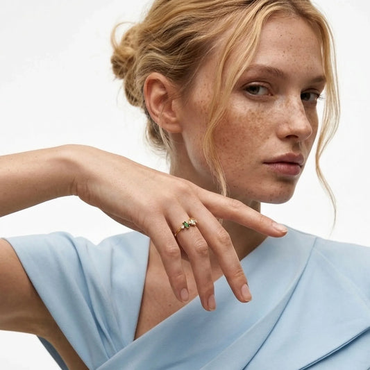 Woman wearing a gold ring on her finger against a neutral background
