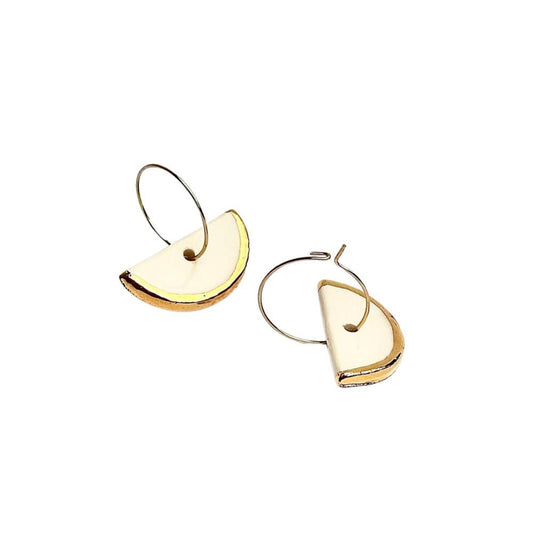 Doraluna white ceramic dangle earrings with gold luster shown on a model's ear