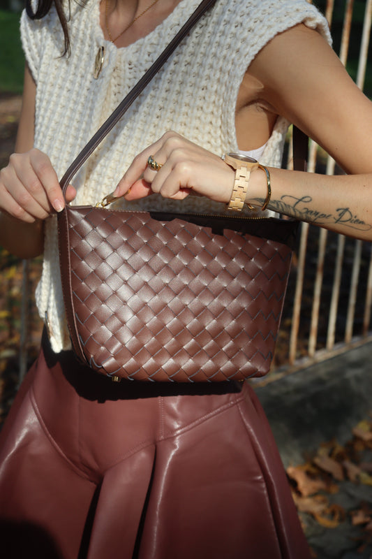 Model met bruine gevlochten leren pouch-tas met lange schouderband bij een witte gebreide top