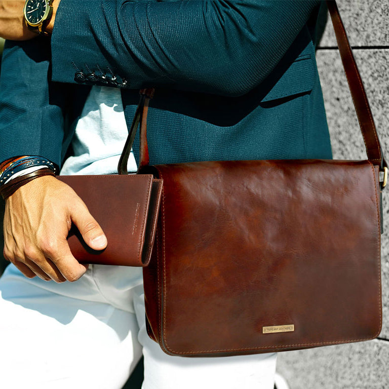 Braune Leder-Messengertasche zum Umhängen mit kleiner Geldbörse, getragen von einer Person in einem petrolfarbenen Blazer