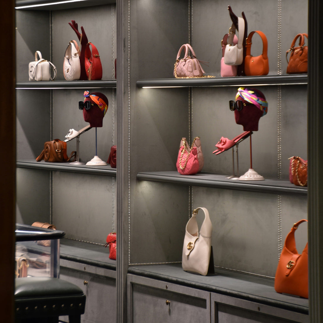 Boutique display of colorful leather handbags arranged on gray shelves.