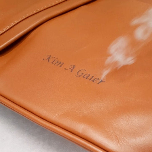 Incisione laser di un nome su una borsa italiana in pelle color caramello presso lo stabilimento Tuscany Leather