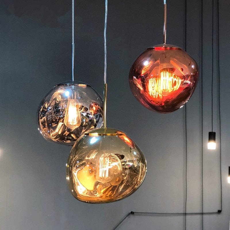 Three glass pendant lights in amber and clear tones hang from the ceiling in a modern foyer