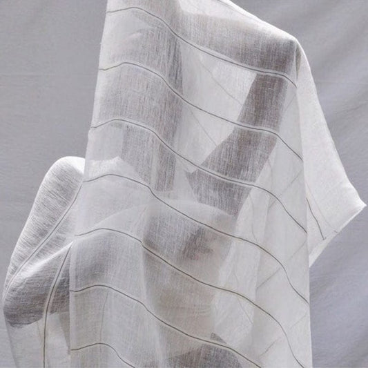 White linen scarf with soft grey stripes draped to show its light texture.
