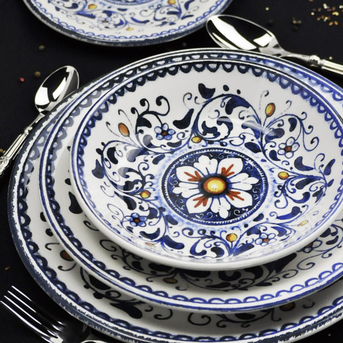Gros plan sur des assiettes décoratives bleues et blanches à motifs floraux avec des couverts sur une table sombre