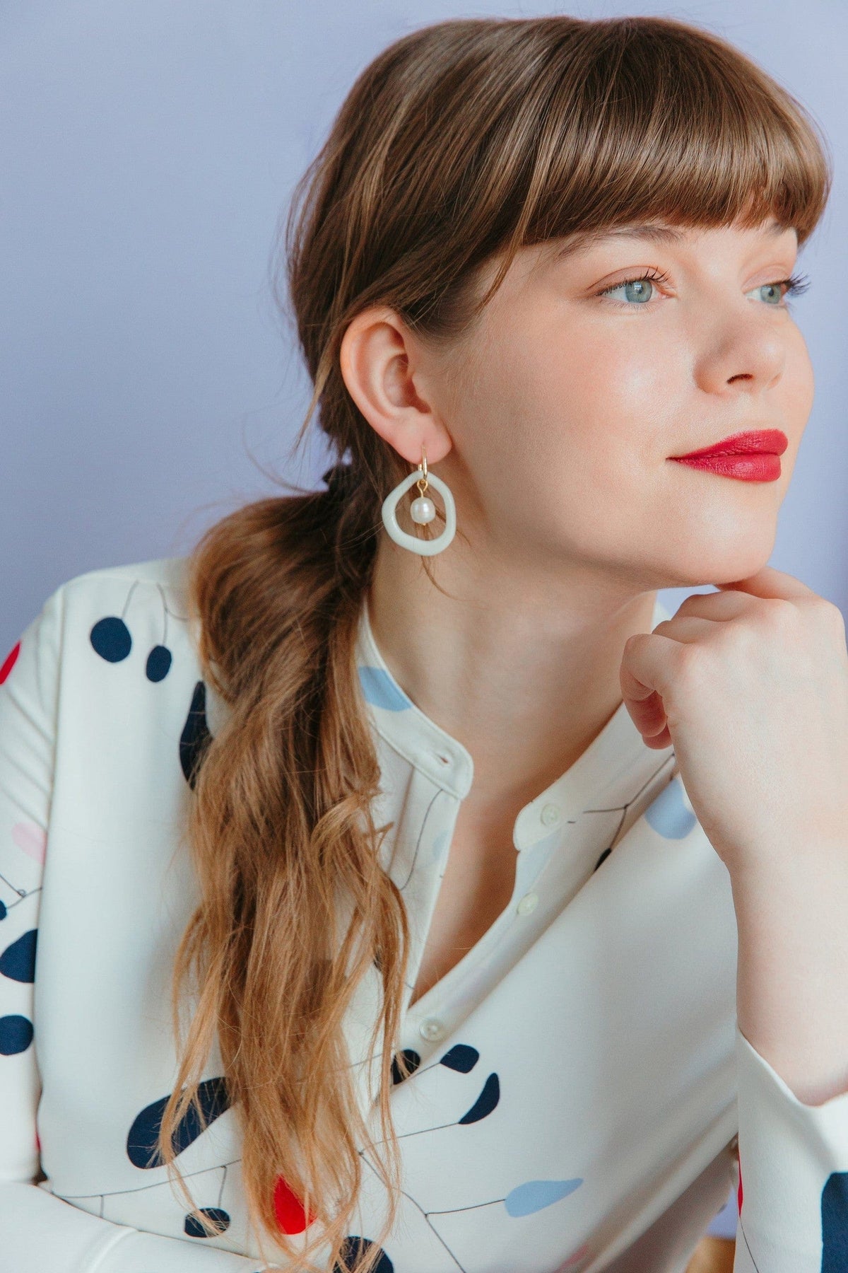 Pastel ceramic circular earrings with a pearl bead worn by a model