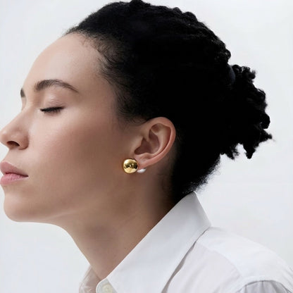 Vrouw draagt gold earrings with a pearl back tegen witte achtergrond