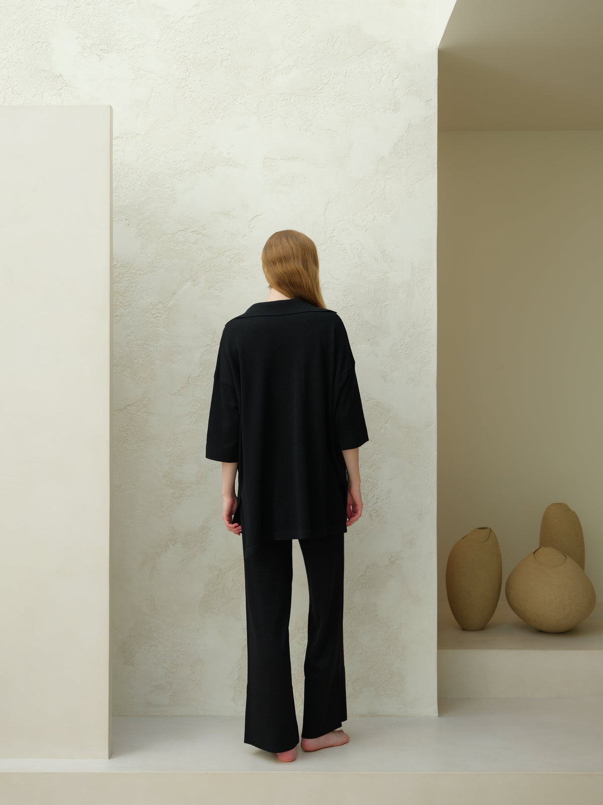 Back view of a mannequin portant a black Merino Wool Maxi Polo with an oversized silhouette