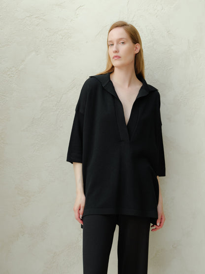 Femme en black oversized merino wool maxi polo with deep V-neck and relaxed silhouette.