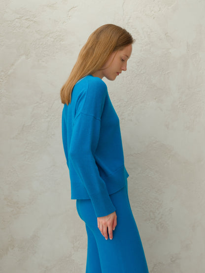 Side profile of model in blu cashmere mix maglione girocollo con matching knit pants.