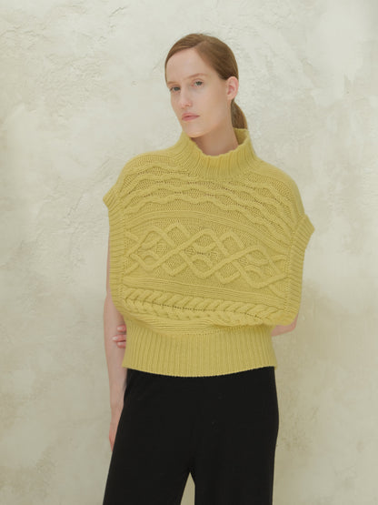 Front view of a modella con a yellow cashmere mix maxi tunica a trecce con a high ribbed collar e bold cable patterns.