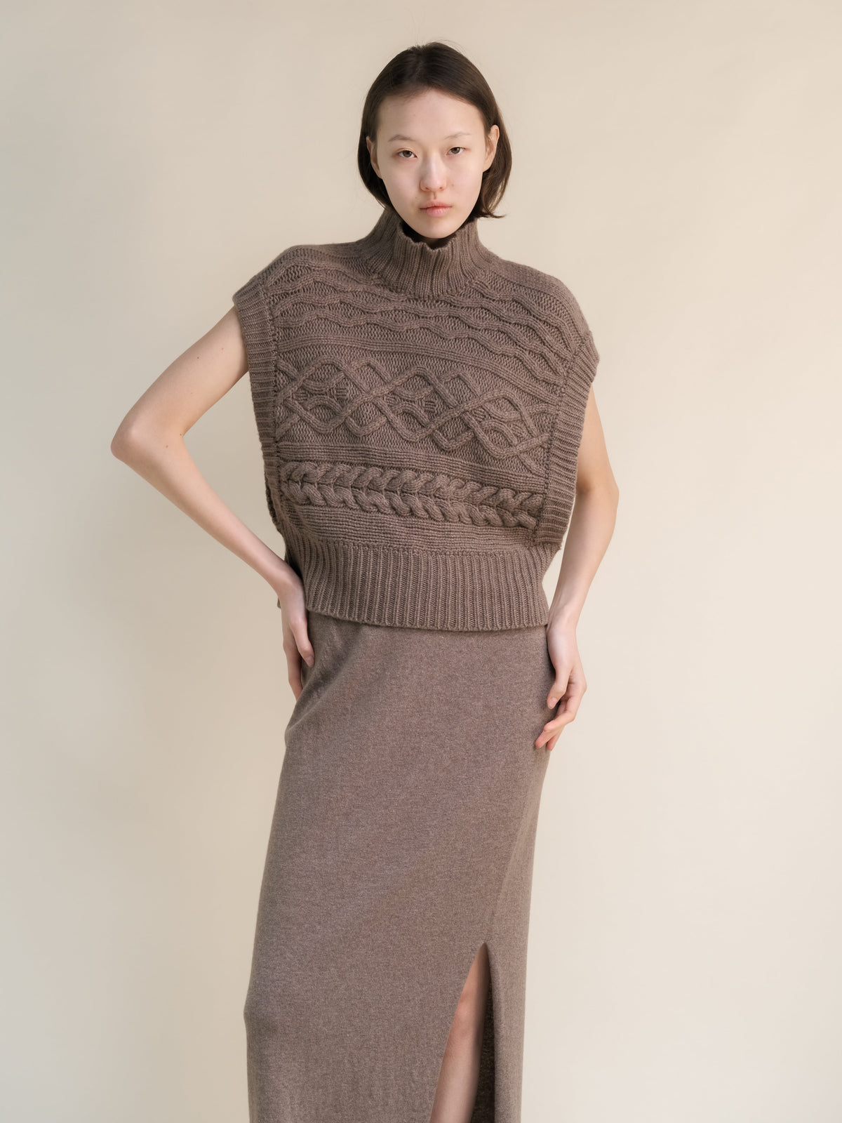 Taupe cashmere mix maxi tunica a trecce styled as a sleeveless collo alto poncho con intricate knit patterns e side openings.