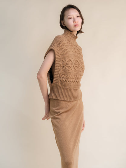 Profile view of a modella con a cuoio cashmere mix maxi tunica a trecce con a high ribbed neck e bold knit patterns.