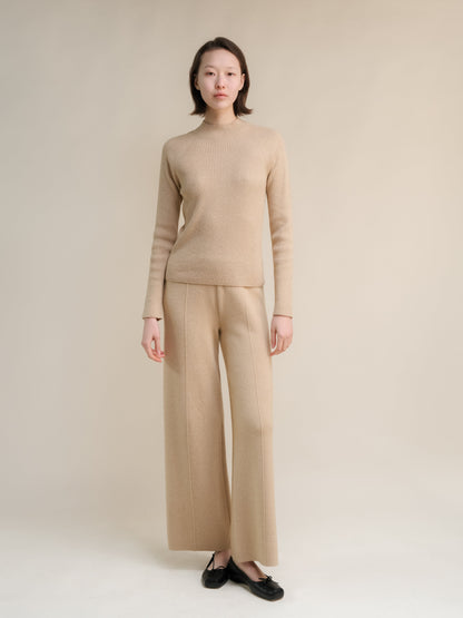 Crema 3D-Knit cashmere mix maglione a coste con collo alto on a model con matching wide-leg trousers.