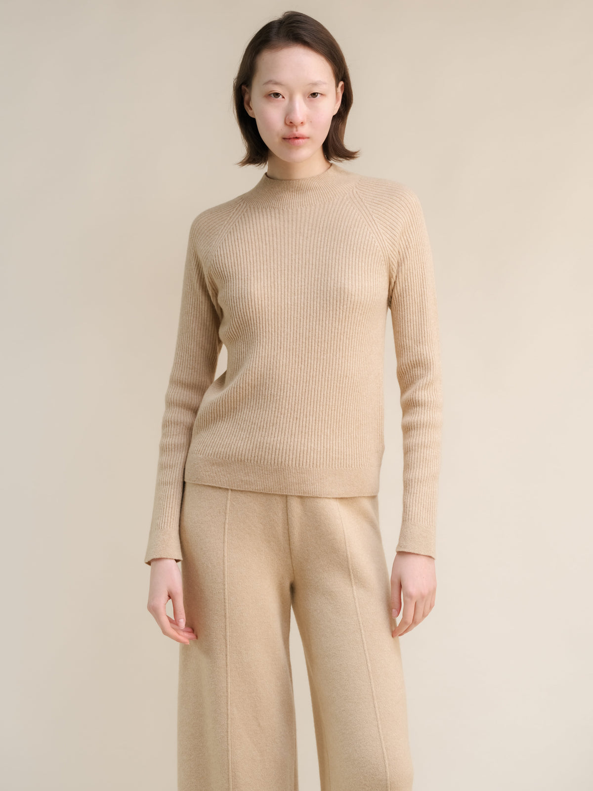Beige 3D-Knit cashmere mix maglione a coste con collo alto on a model con coordinating beige trousers.