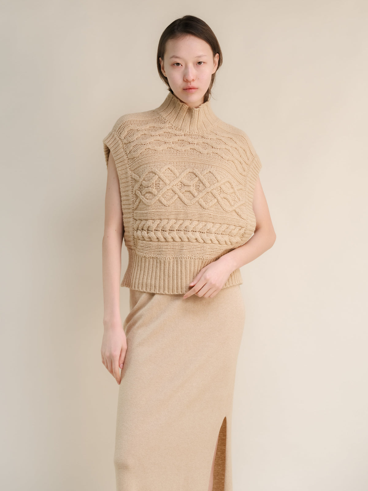 Beige sleeveless cashmere mix maxi tunica a trecce on a model con a chunky knit pattern e orlo a coste.