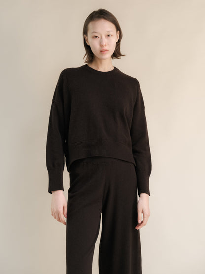Modella con a dark marrone cashmere mix maglione girocollo con pantaloni coordinati a gamba larga.