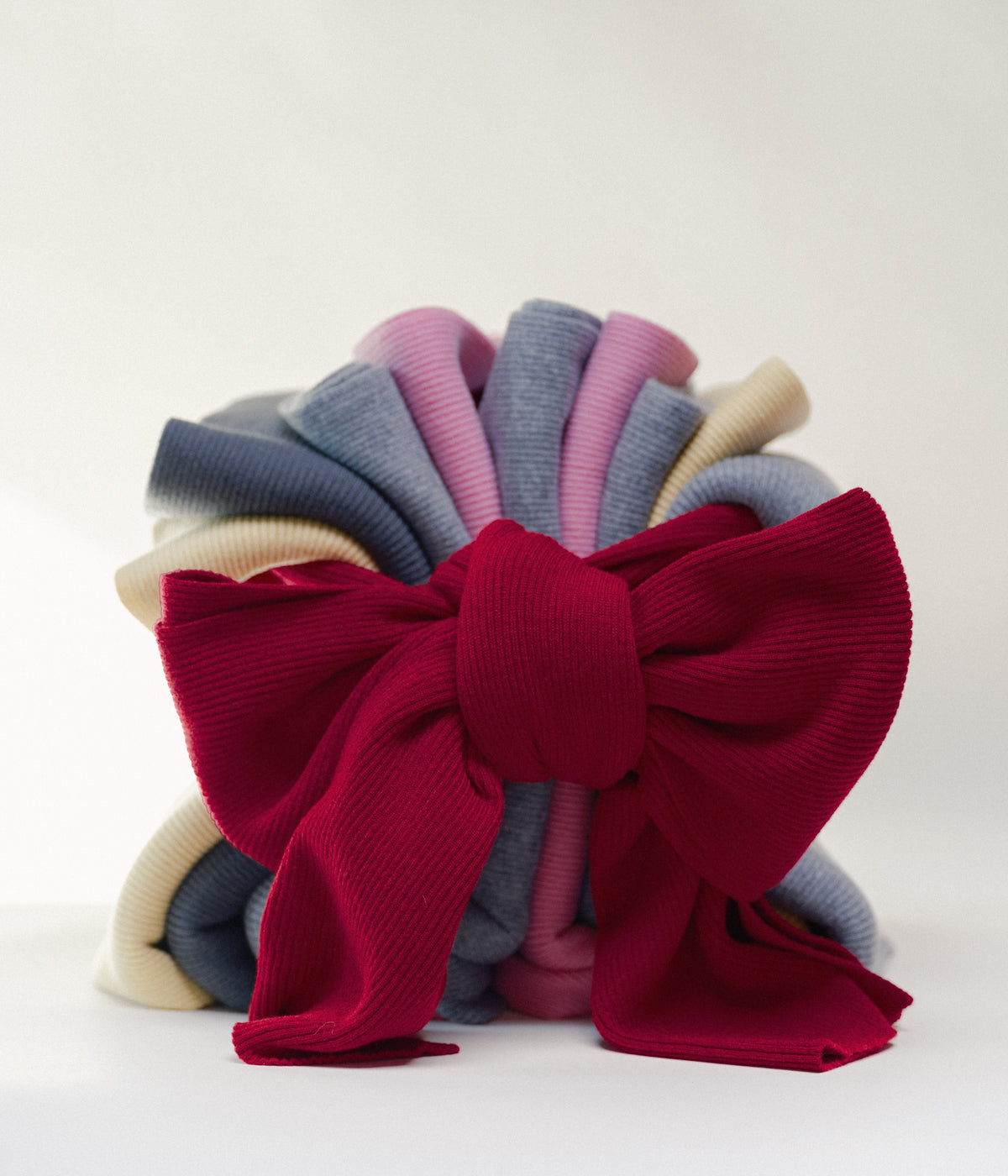 Stack of colorful casmere scarves with one tied in a large red bow vor weissem Hintergrund