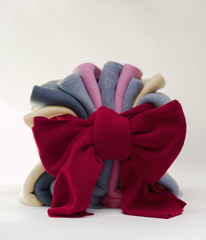 Stack of colorful casmere scarves with one tied in a large red bow vor weissem Hintergrund