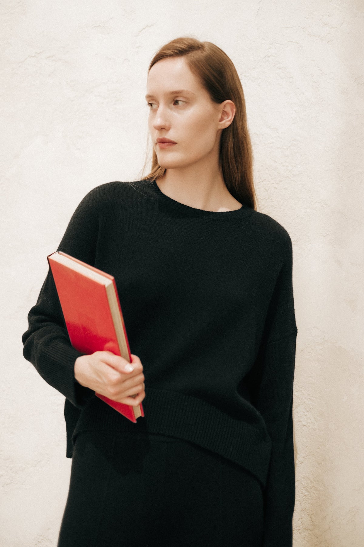 Modella con a nero cashmere mix maglione girocollo holding a rosso book.