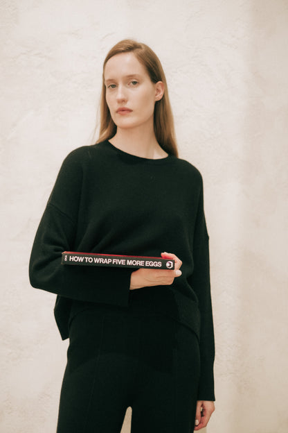 Modella con a nero cashmere mix maglione girocollo holding a rosso book at the hip