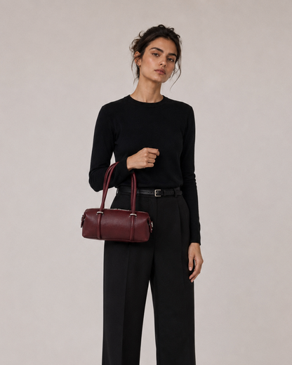 Femme tenant un sac à main bordeaux sur fond uni