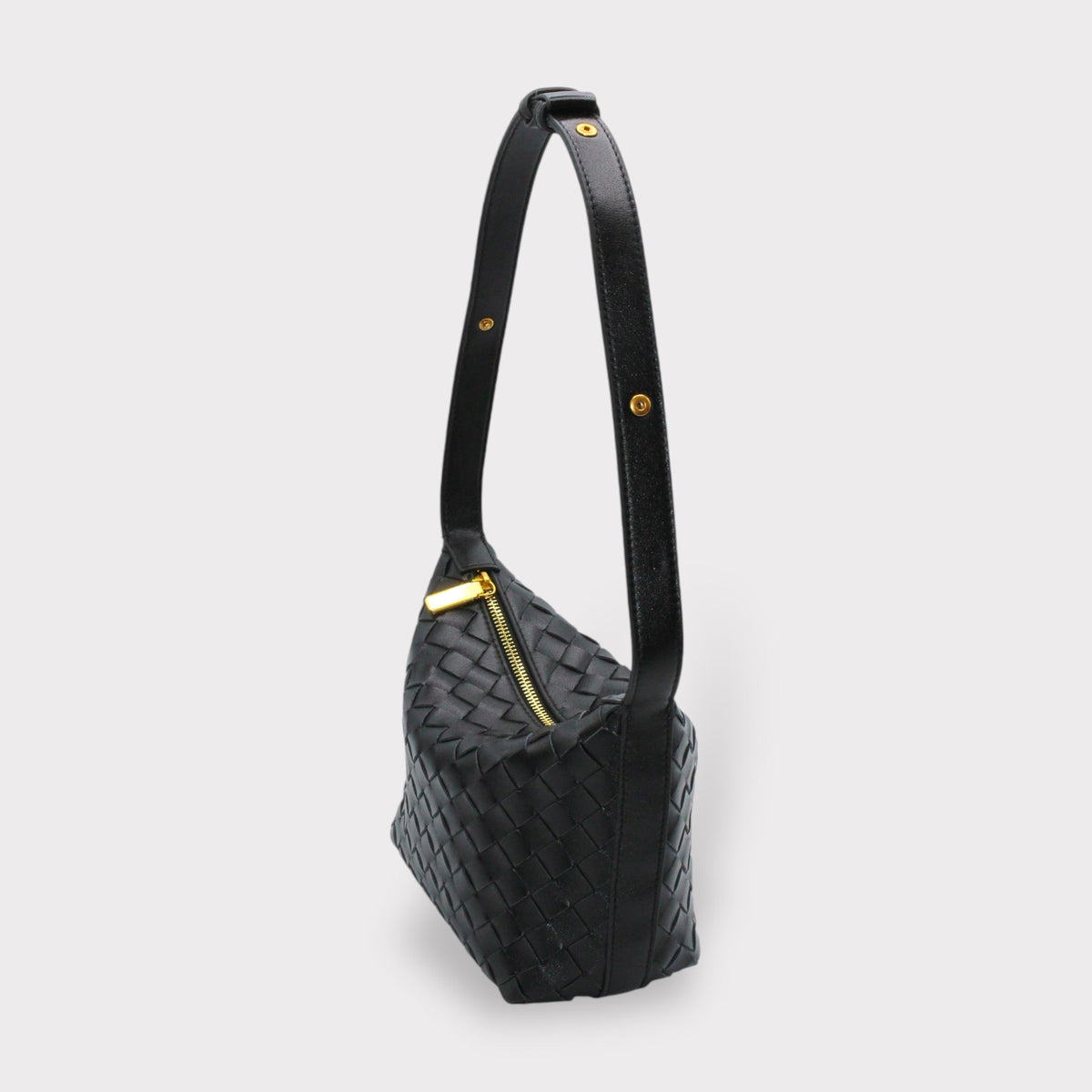 Side view of black woven leather box pouch with a long strap and gold hardware
