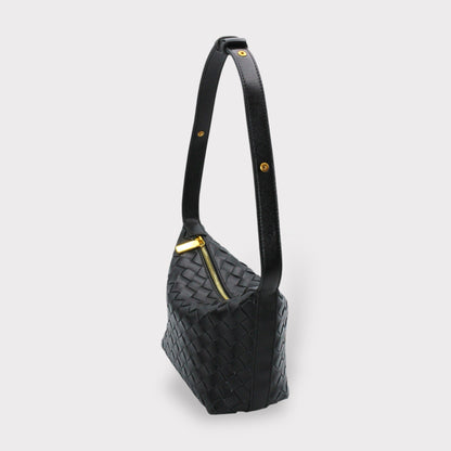 Side view of black woven leather box pouch with a long strap and gold hardware
