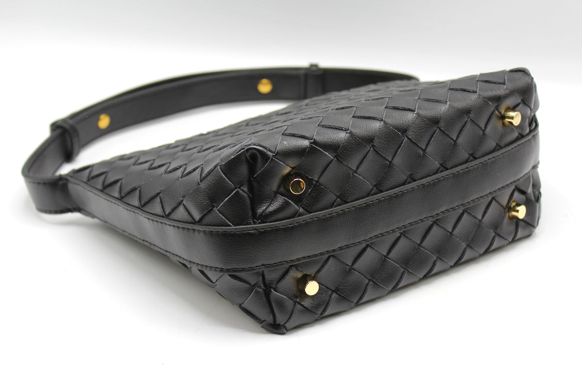 Angled view of black woven leather box pouch showing gold studs and stitched edges