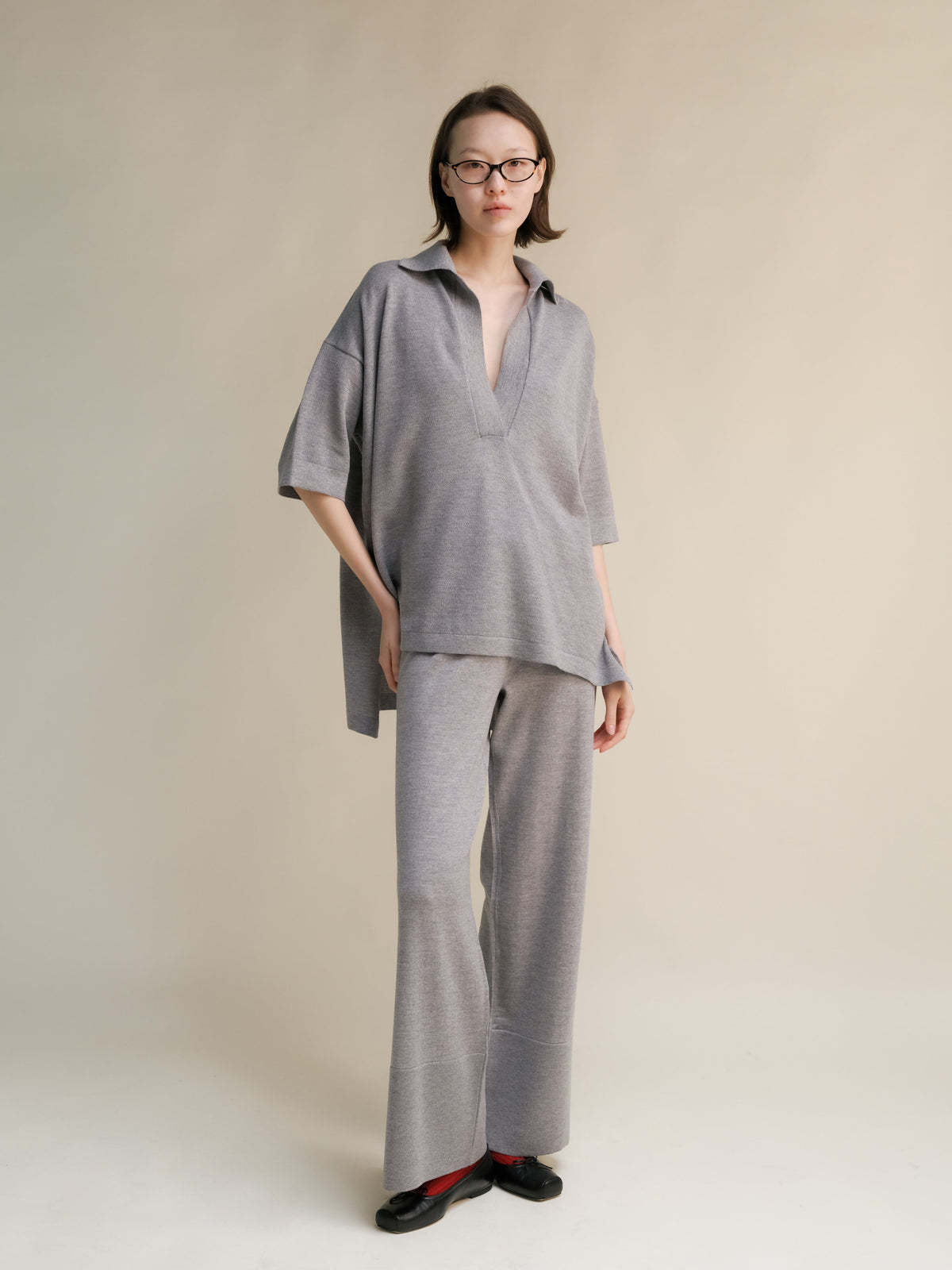 Mannequin portant grey oversized merino wool maxi polo with a collared neckline and pantalon large assorti.