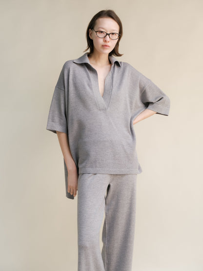 Femme en oversized light gray merino wool maxi polo with deep V-neck and pantalon large assorti.