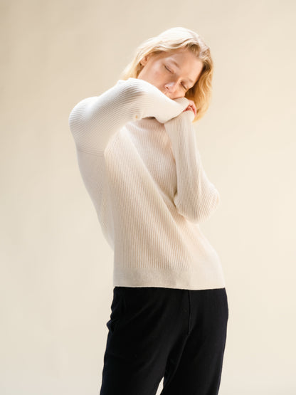 Donna con bianco ribbed cashmere mix mock neck sweater, vista posteriore con arms raised.