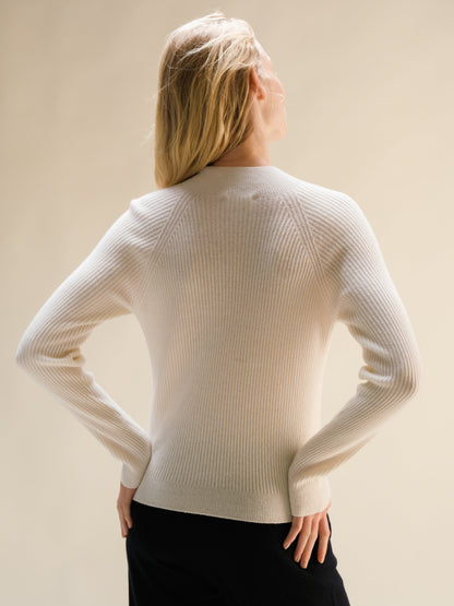 Modella con crema ribbed cashmere mix mock neck sweater, vista posteriore con hes on hips.