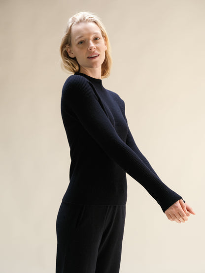 Modella con navy cashmere mix maglione a coste con collo alto in a relaxed pose con texture in maglia 3D.