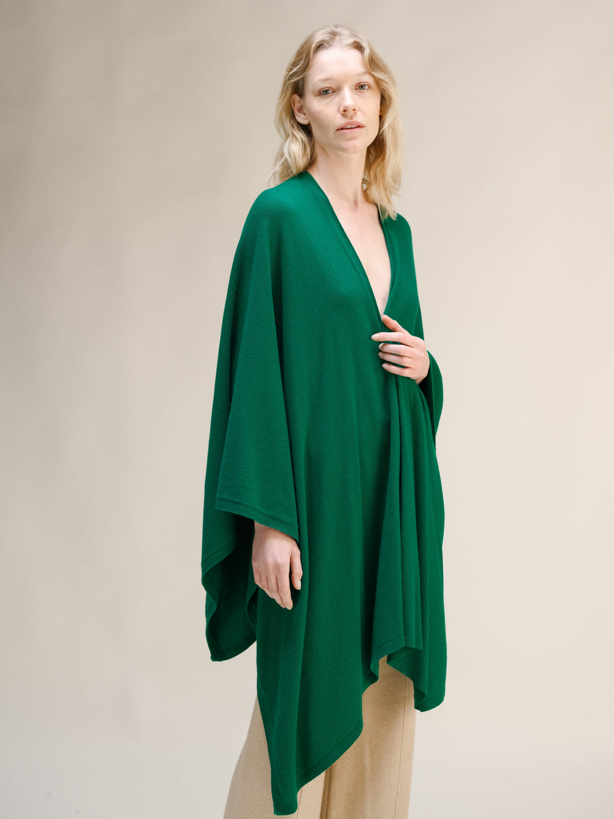 Modella con maxi cappa verde smeraldo in misto cashmere con davanti avvolgente su pantaloni beige