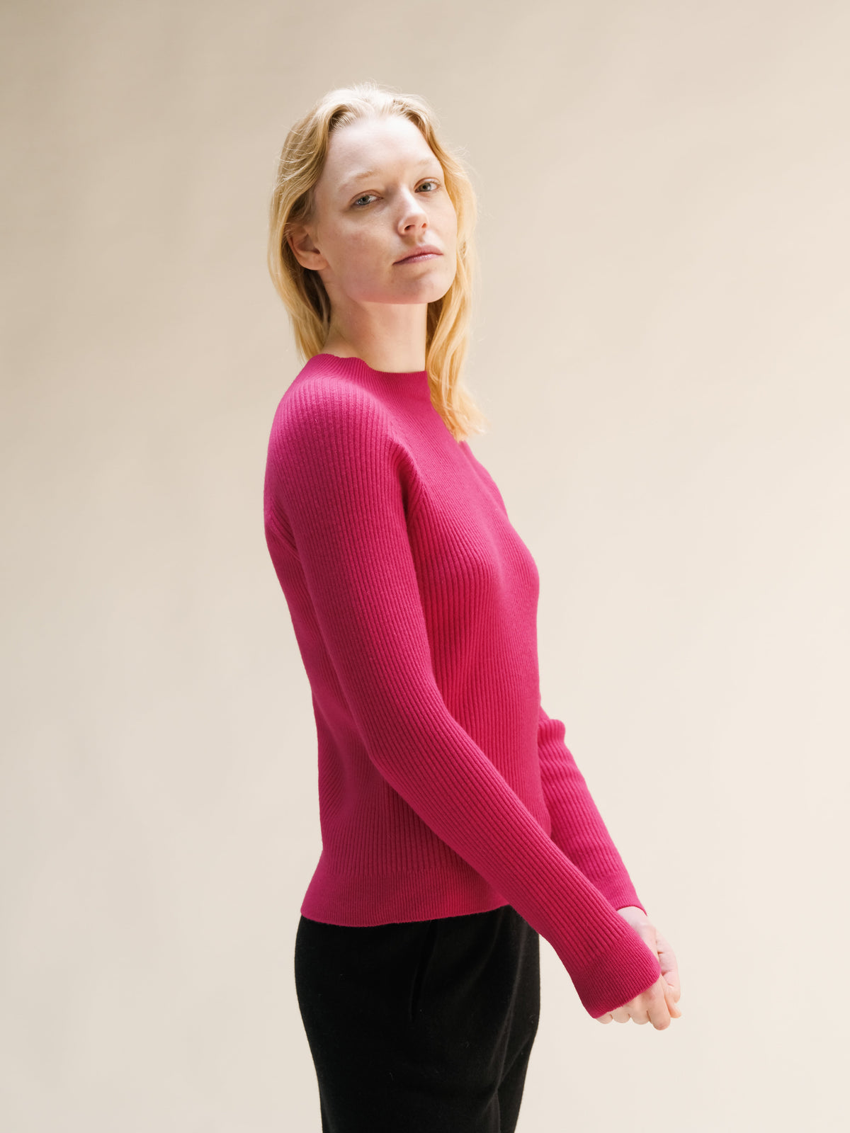Side view of vibrant rosa maglione a coste con collo alto.