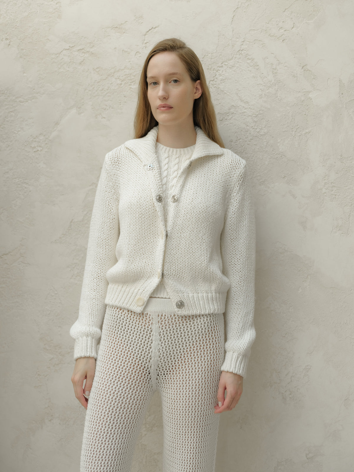 Front view of a model wearing a white textured knit bomber jacket with a collar and metal buttons.