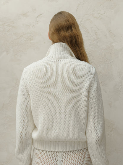 Back view of white chunky knit bomber jacket with a tall ribbed collar.