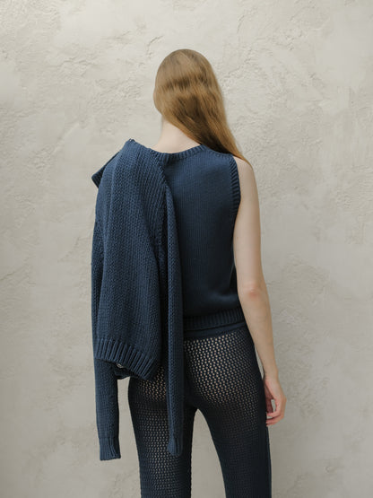 Back view of a model wearing a navy knit top with a cardigan draped over one shoulder and sheer knit pants
