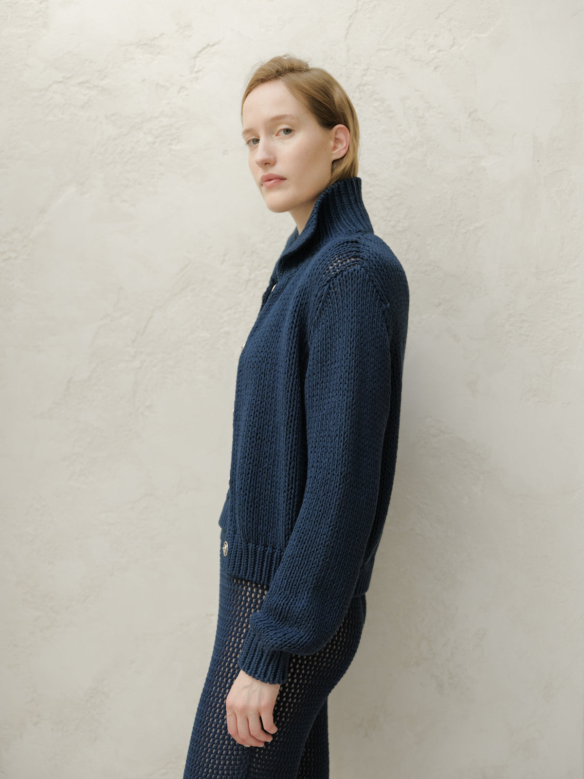 Side profile of a model wearing a navy Fine Cotton Bomber Jacket with a chunky knit texture