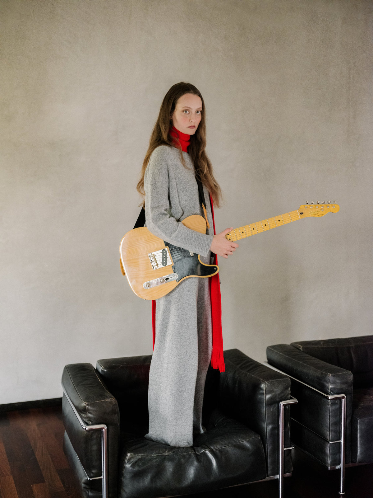Modella con a grigio cashmere mix maglione girocollo as part of a layerosso outfit con a rosso scarf while holding an electric guitar