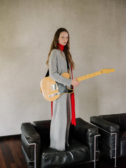 Modella con a grigio cashmere mix maglione girocollo as part of a layerosso outfit con a rosso scarf while holding an electric guitar