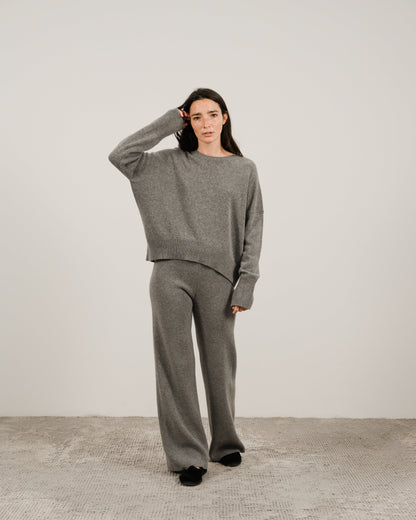 Modella con a grigio oversized cashmere mix maglione girocollo con pantaloni coordinati a gamba larga in a studio.