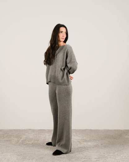Donna con grigio cashmere mix maglione girocollo con pantaloni coordinati a gamba larga steing in a studio setting.