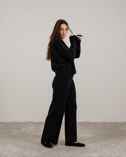 Full body vista laterale of a woman in a nero cashmere mix maglione girocollo con pantaloni a gamba larga