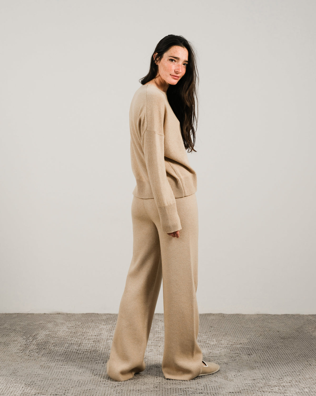 Beige cashmere mix maglione girocollo con pantaloni coordinati a gamba larga on a model shown in a vista laterale