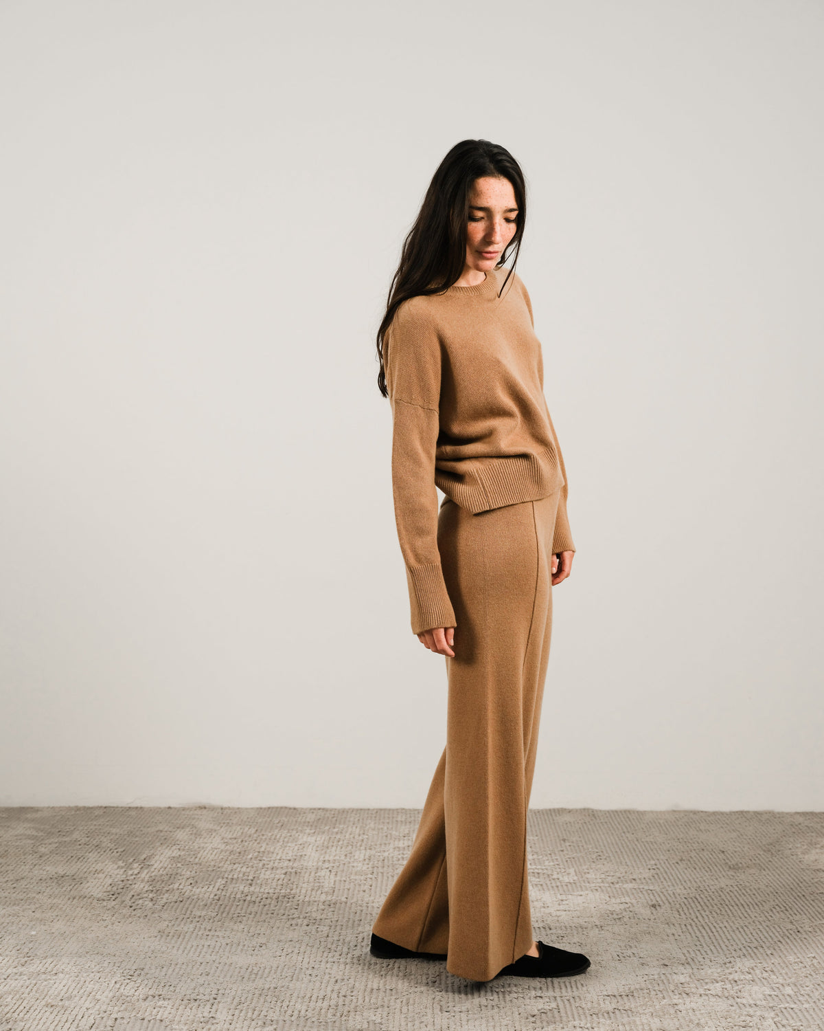 Side view of a donna con a camel cashmere mix maglione girocollo con pantaloni coordinati a gamba larga