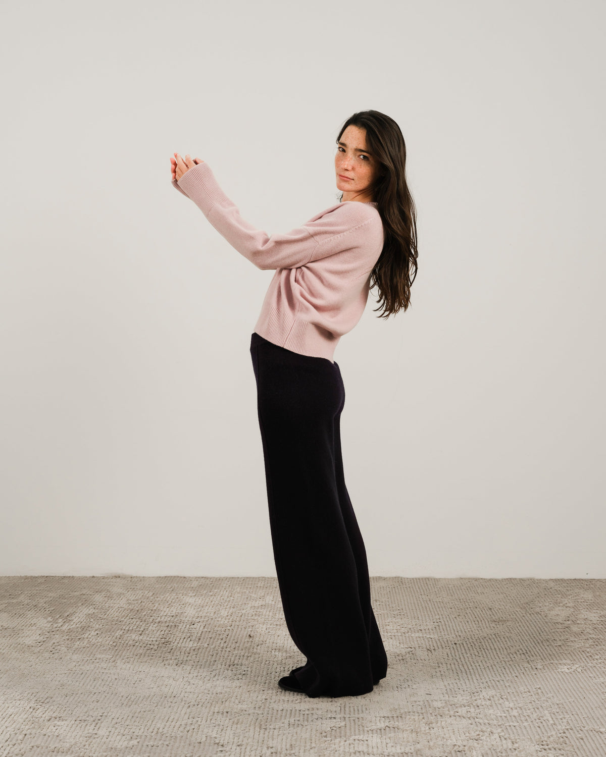 Modella con pale rosa cashmere mix maglione girocollo con nero pantaloni a gamba larga in a side pose