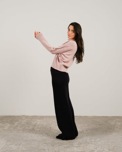 Modella con pale rosa cashmere mix maglione girocollo con nero pantaloni a gamba larga in a side pose