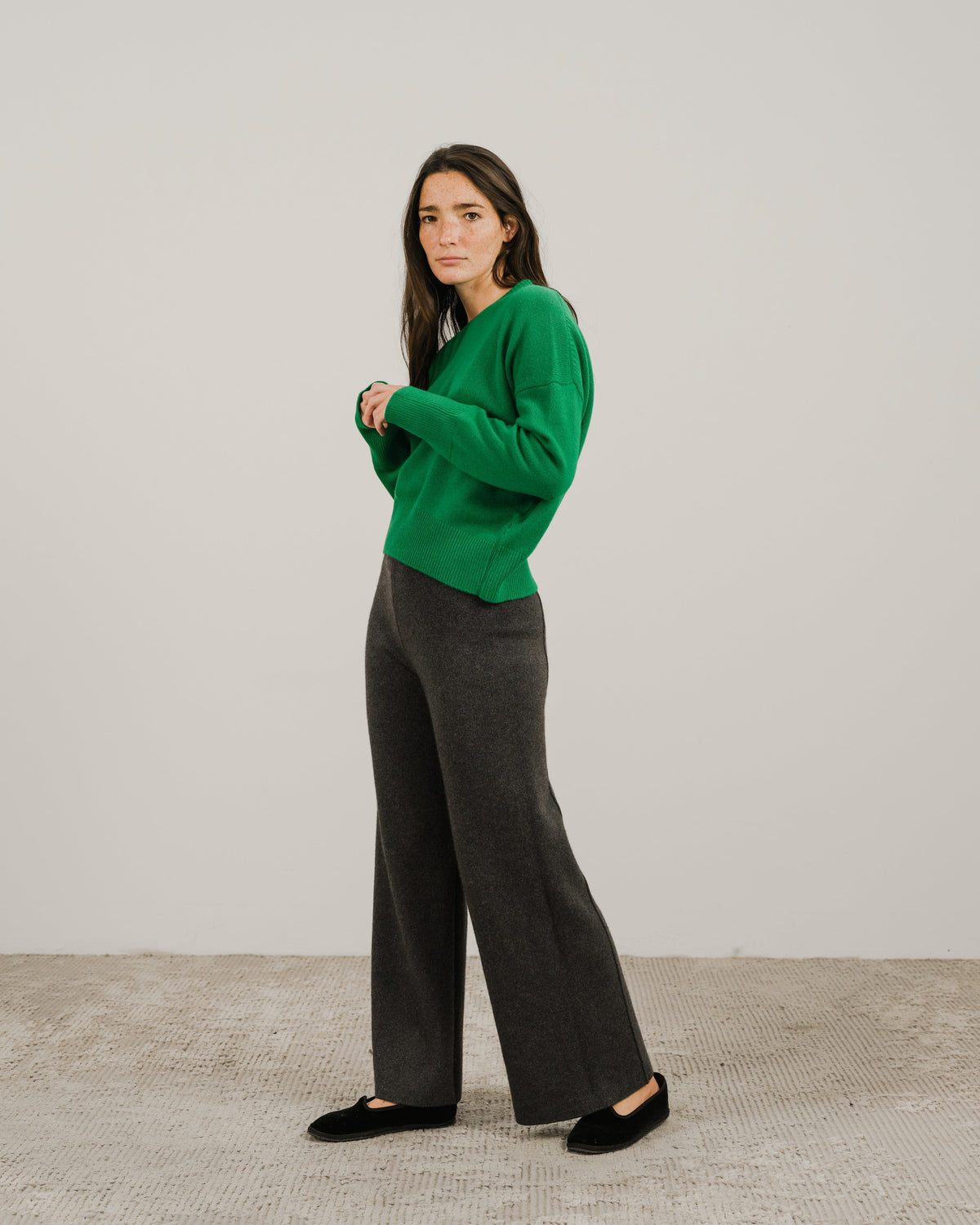 Full body shot of a model in a verde brillante cashmere mix maglione girocollo con dark grigio pantaloni a gamba larga